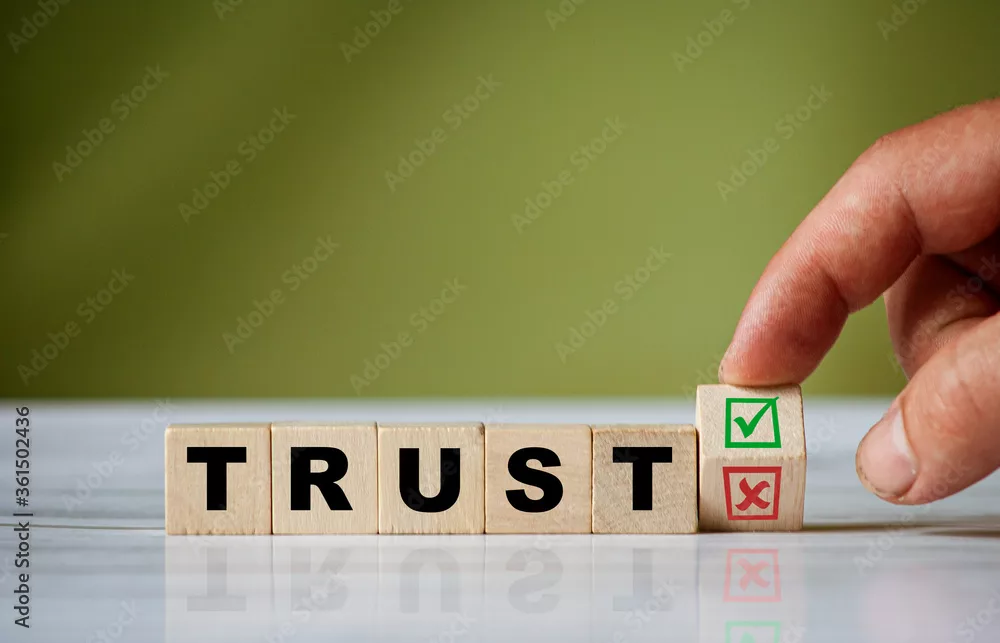 The hand turns the wooden cube and changes the word TRUST with green positive tick check box and red reject X check box.